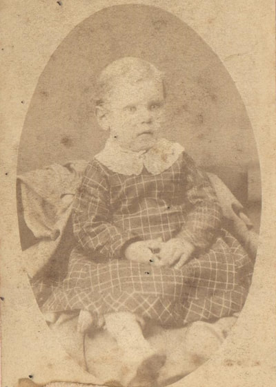 Young boy with blonde hair seated in gown