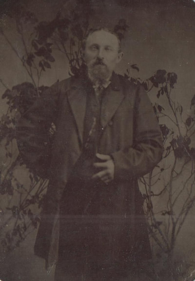 Man with goatee in overcoat standing with hand behind back