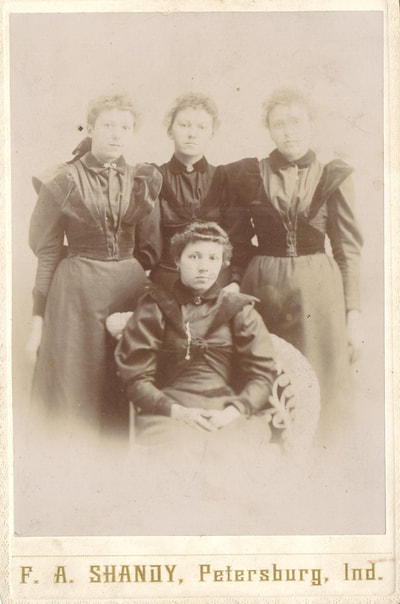  Group of three women standing behind woman seated