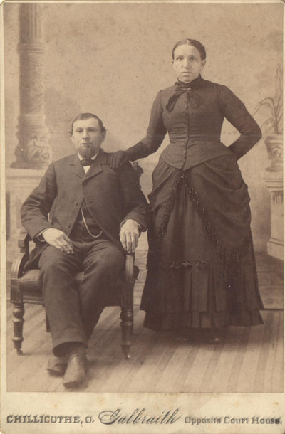 Man sitting next to woman standing in dress clothes