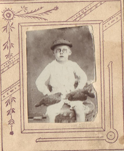 Boy with eye glasses seated with chickens