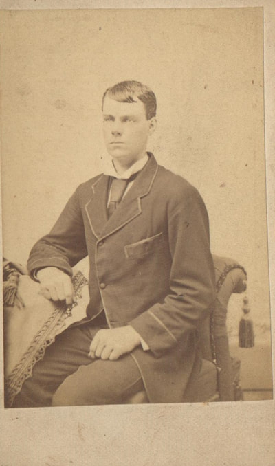 Young man in dress clothes seated on chair 