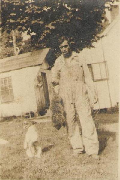 Man in overalls holding dead animal