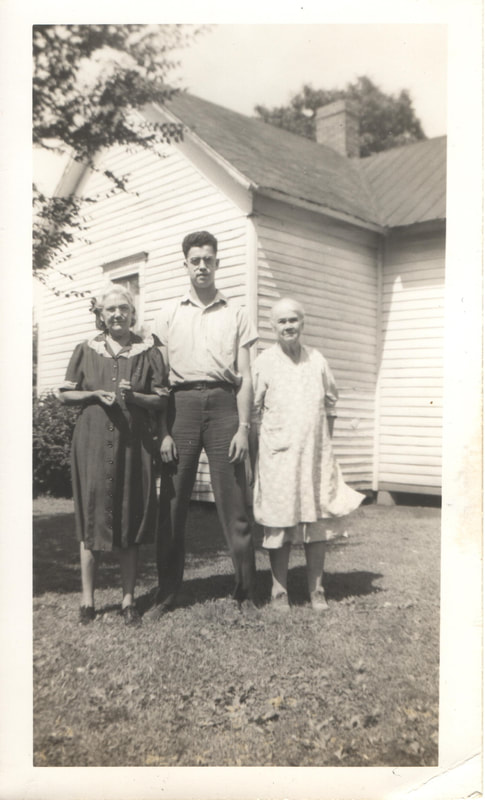 Elderly women and tall man standing together in front of house