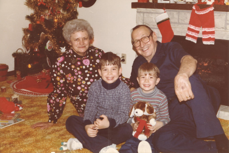 Elderly man and woman seated with children at Christmas gathering 
